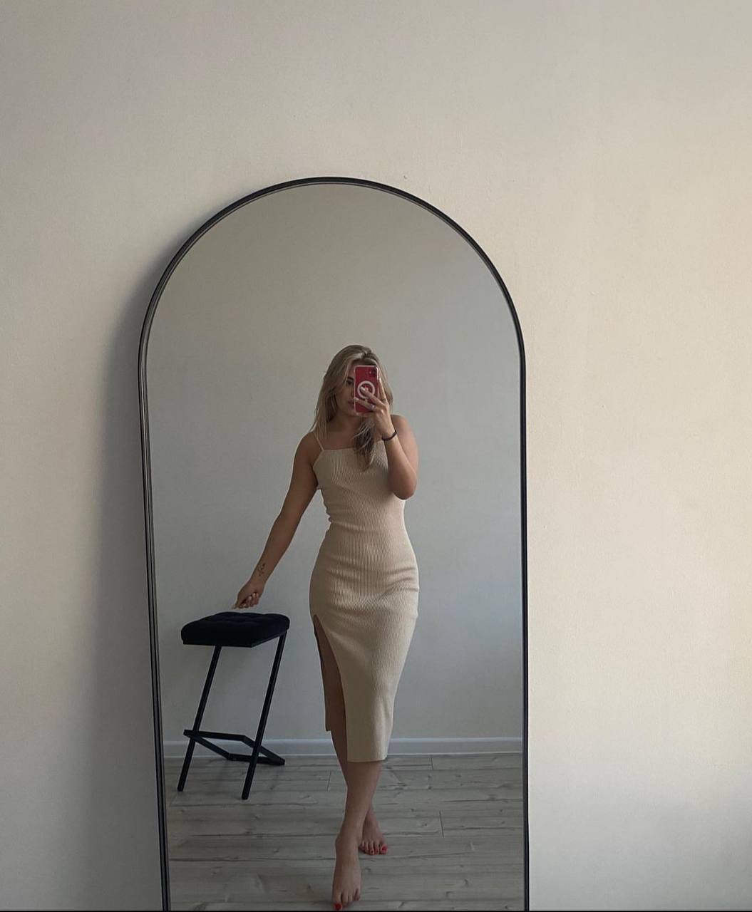 Blonde fashion model taking a mirror selfie in a beige bodycon dress with minimalist style.