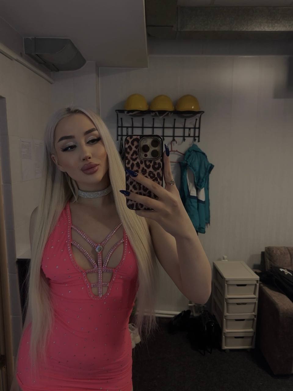 glamorous blonde woman taking mirror selfie in pink rhinestone mini dress with long straight hair
