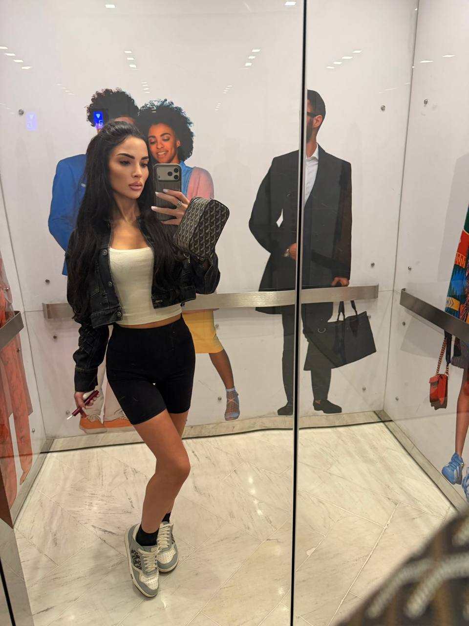 Beautiful VIP escort model wearing casual fashion and taking a mirror selfie in a luxury building elevator
