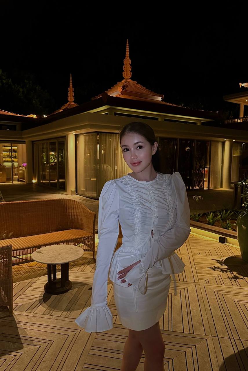 Beautiful Asian fashion model wearing an elegant white dress at a luxury villa during the evening.