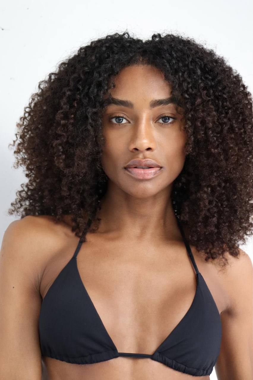 Close up beauty portrait of gorgeous Black fashion model with natural curly afro hair wearing black bikini in professional studio