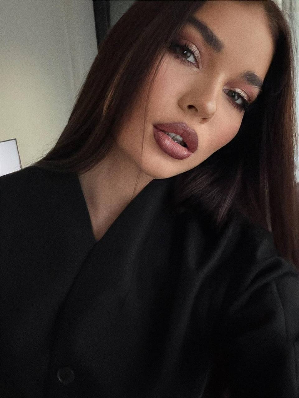 Close-up portrait of a beautiful brunette VIP escort model with glamorous makeup and long dark hair