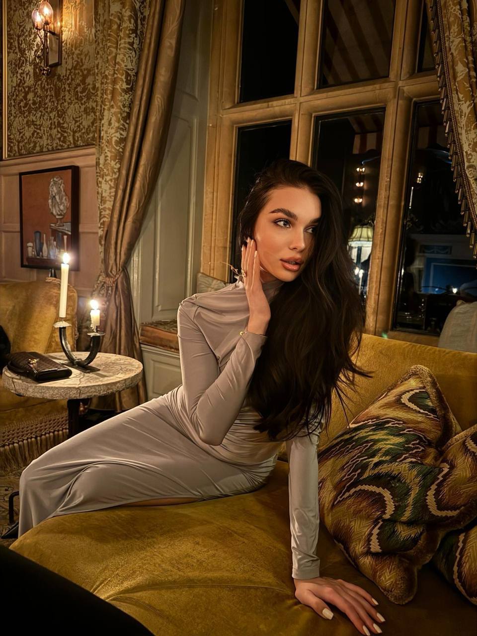 Elegant luxury escort model wearing a beige evening dress in an exclusive hotel lounge