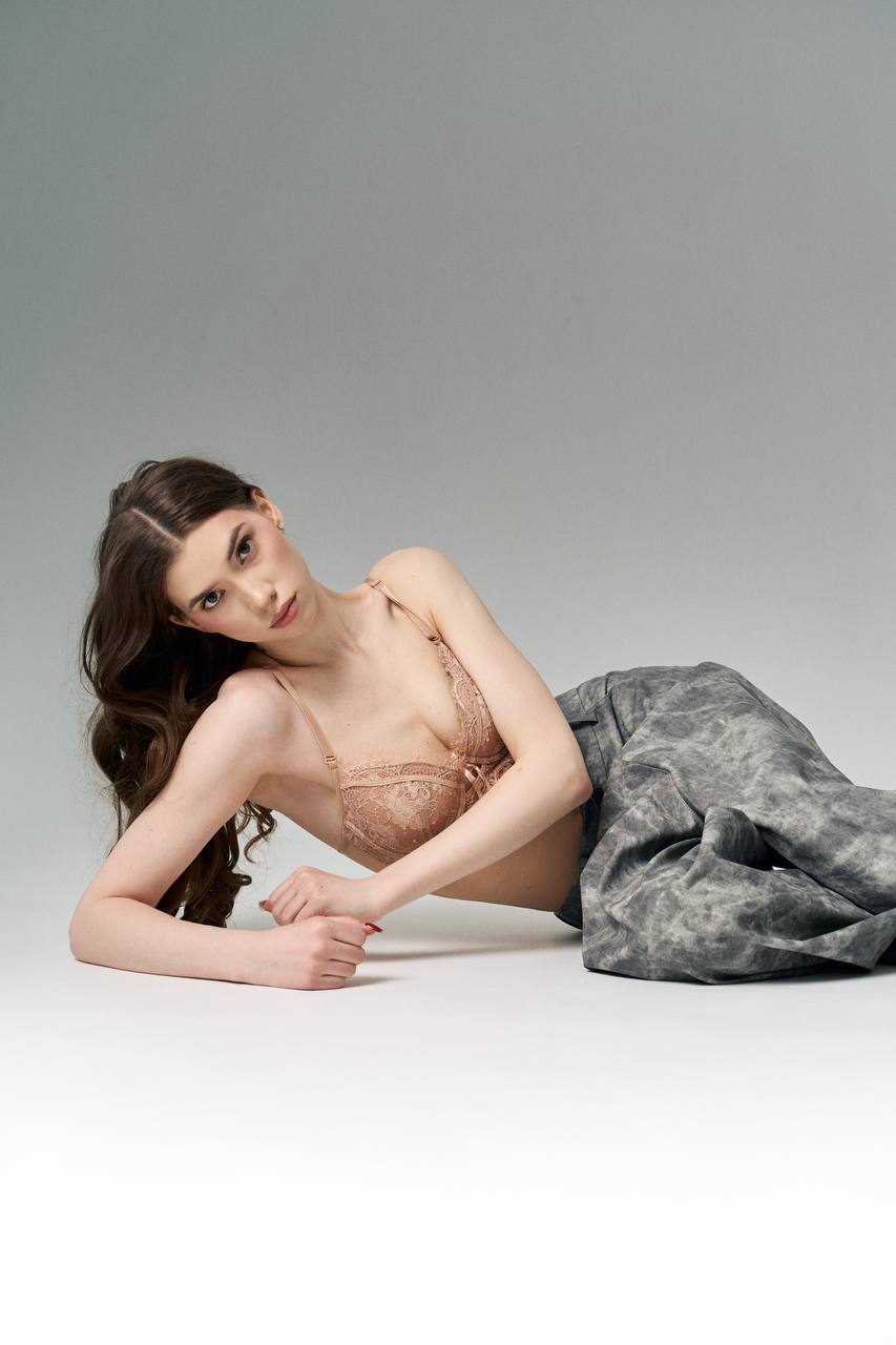 Ultra realistic fashion portrait of a slender brunette woman with long flowing dark brown hair wearing elegant beige lace lingerie and a satin skirt in a minimal studio, luxury magazine editorial, ultra realistic.