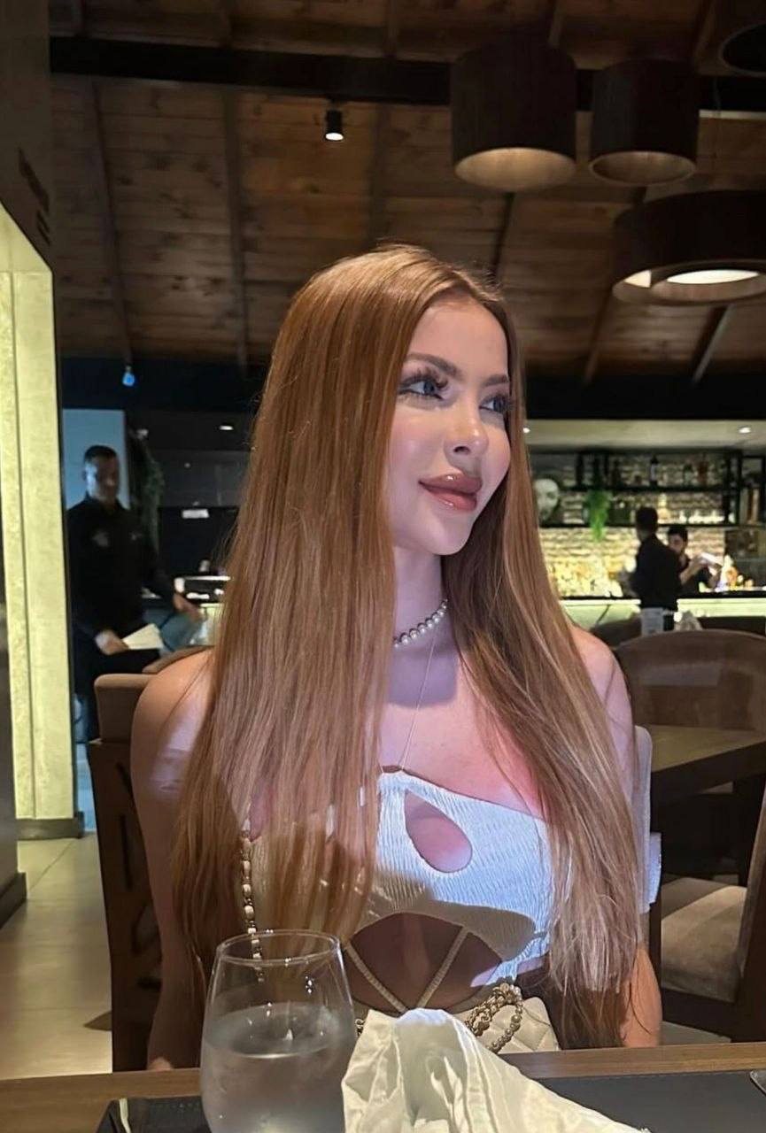 beautiful woman with long light brown hair wearing white cutout dress at elegant restaurant table