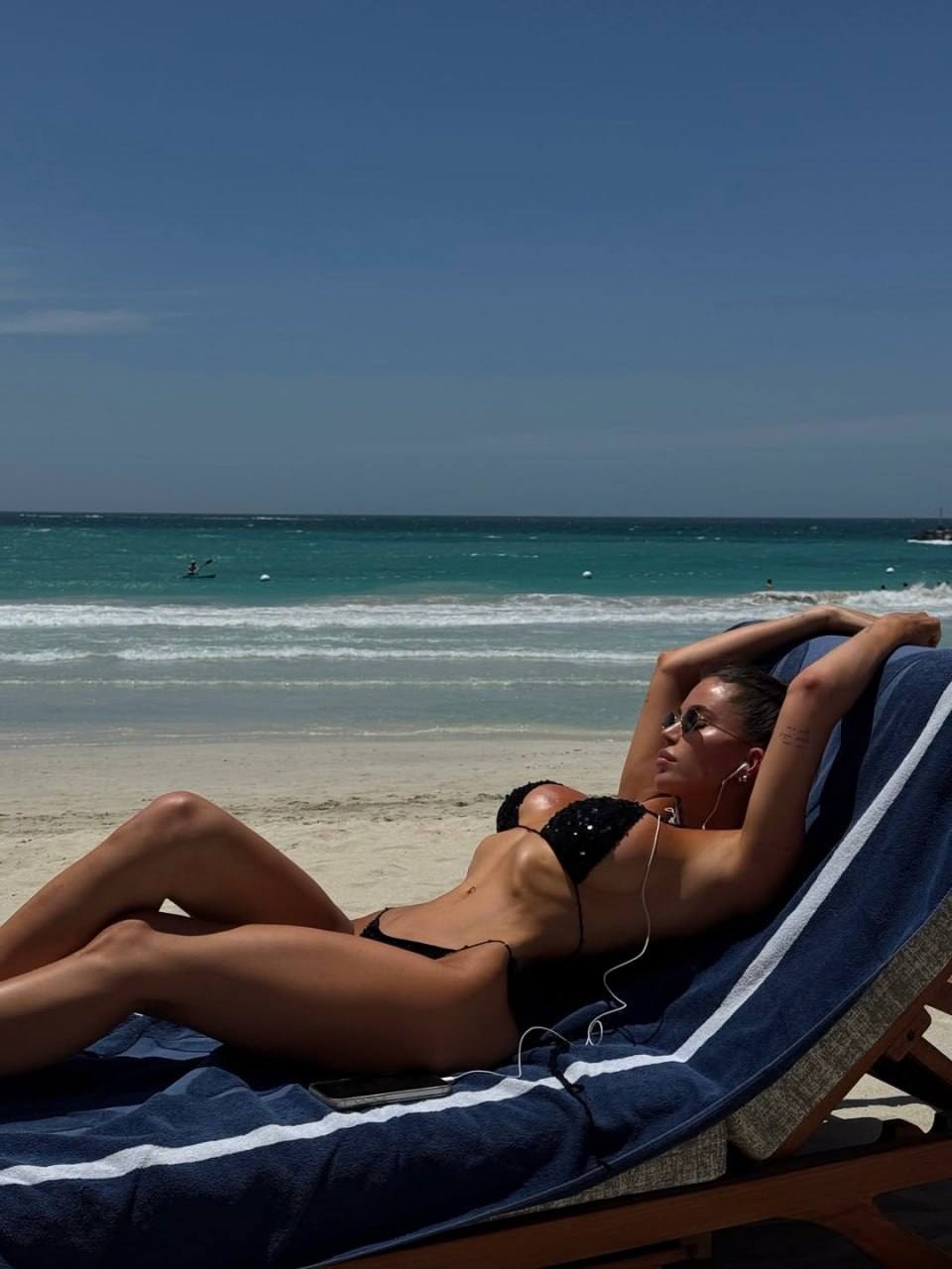 Woman relaxing on a beach lounger in a black bikini with a tropical ocean view