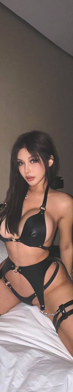 Brunette woman in stylish black lingerie posing on a luxury hotel bed in a modern interior