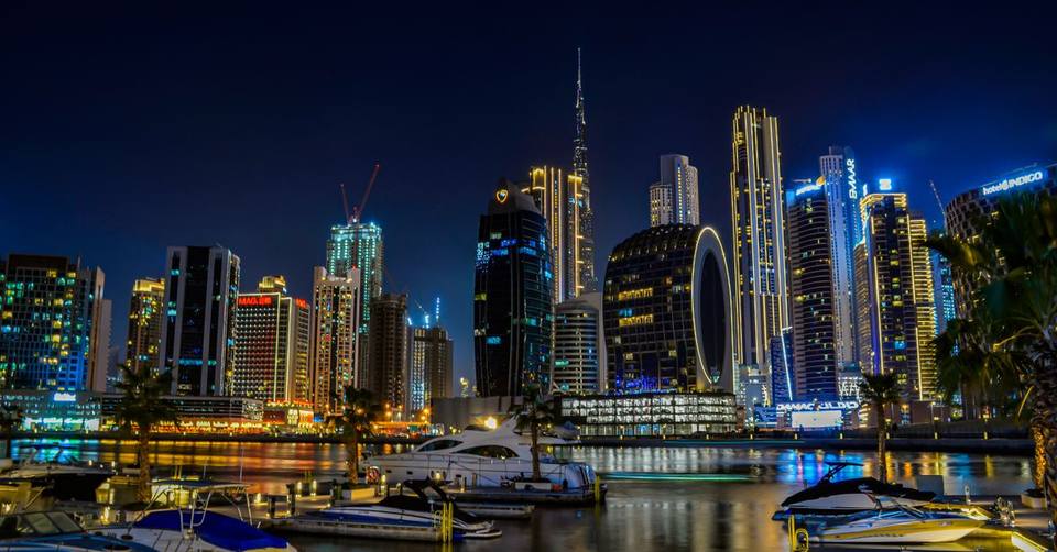 Night panorama of Business Bay with moored yachts, illuminated skyscrapers and Burj Khalifa, Dubai