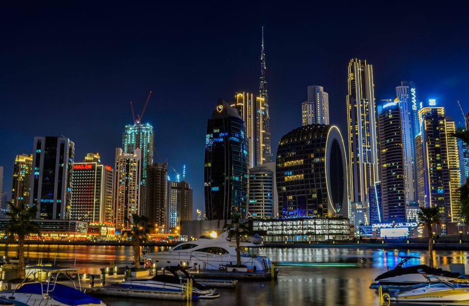 Night panorama of Business Bay with moored yachts, illuminated skyscrapers and Burj Khalifa, Dubai